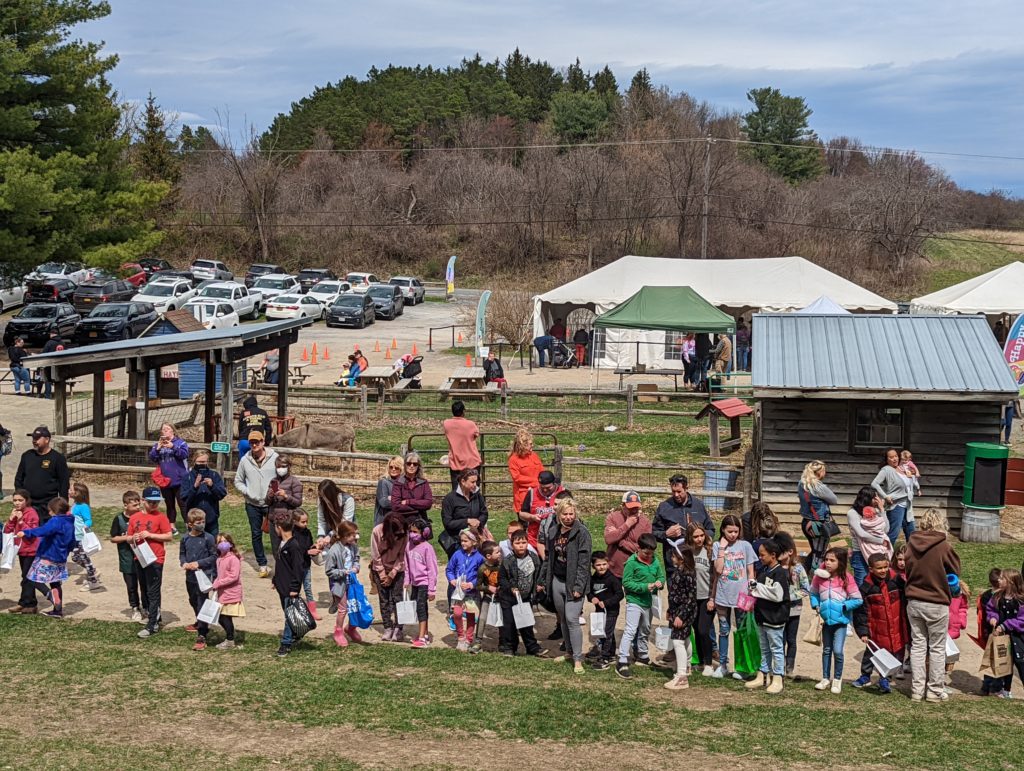 Children standing in line at the base of a mountain on a farm waiting for an easter egg hunt