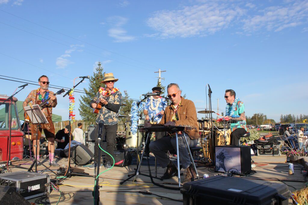 The Swinging Palms playing outdoors on the stage dressed in festive hawaiian accessories.