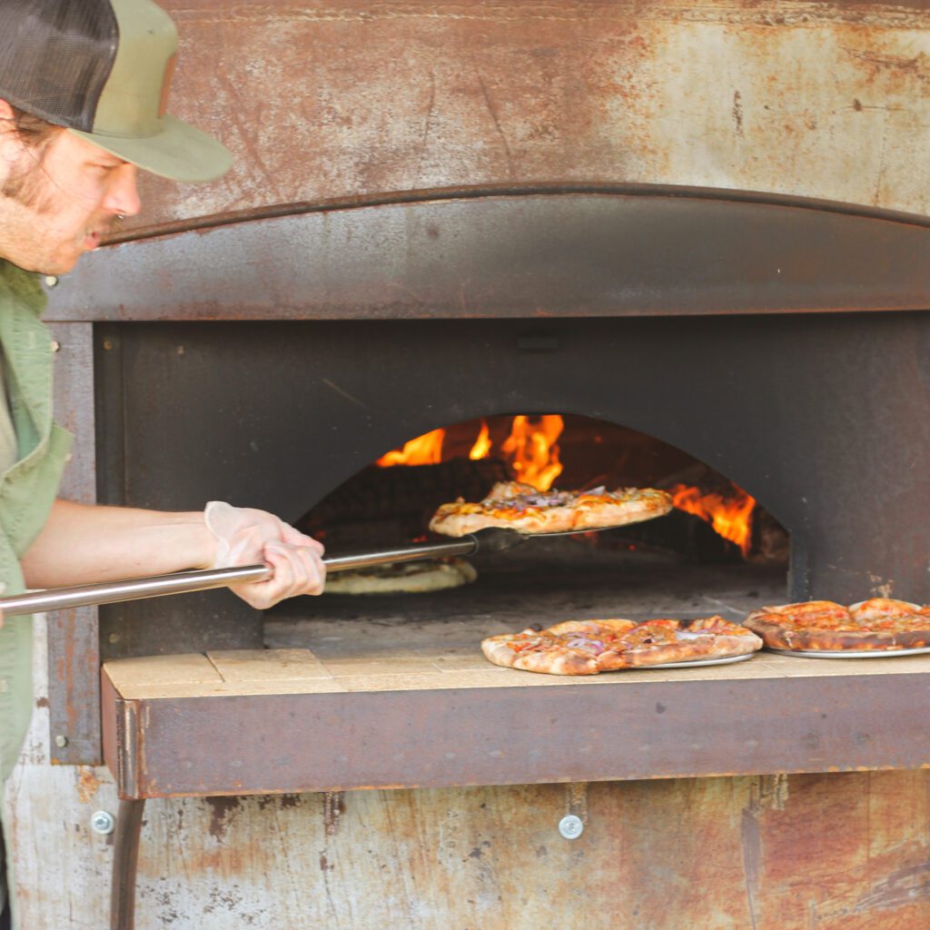 Pizza coming out of the Wood Fired Pizza Oven